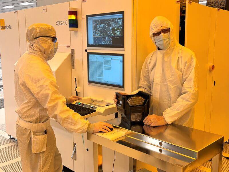 Two people in a cleanroom wearing protective gear