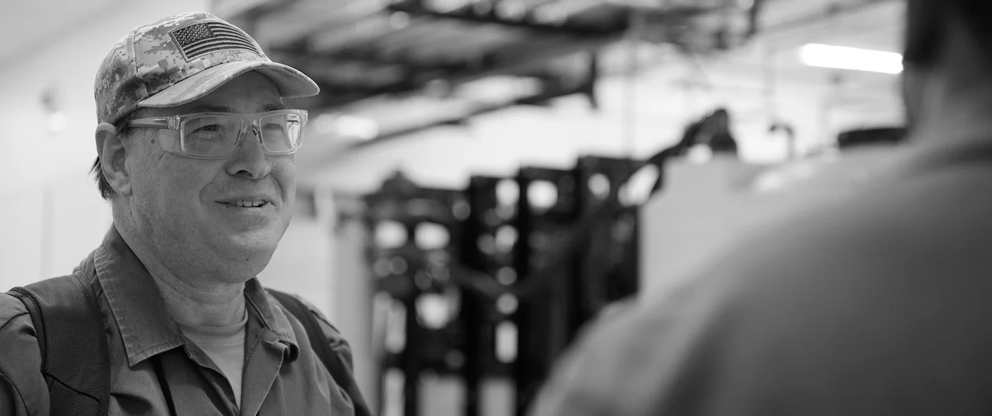 Employee wearing safety glasses and a cap with an American flag in a semiconductor facility.