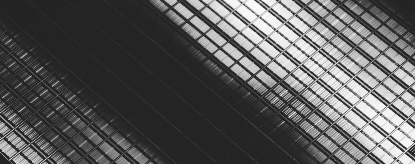 Close-up of a semiconductor wafer substrate with a grid pattern, reflecting light in a diagonal arrangement.
