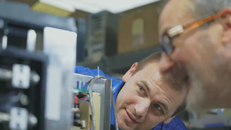 Technicians examining semiconductor equipment in a lab setting.