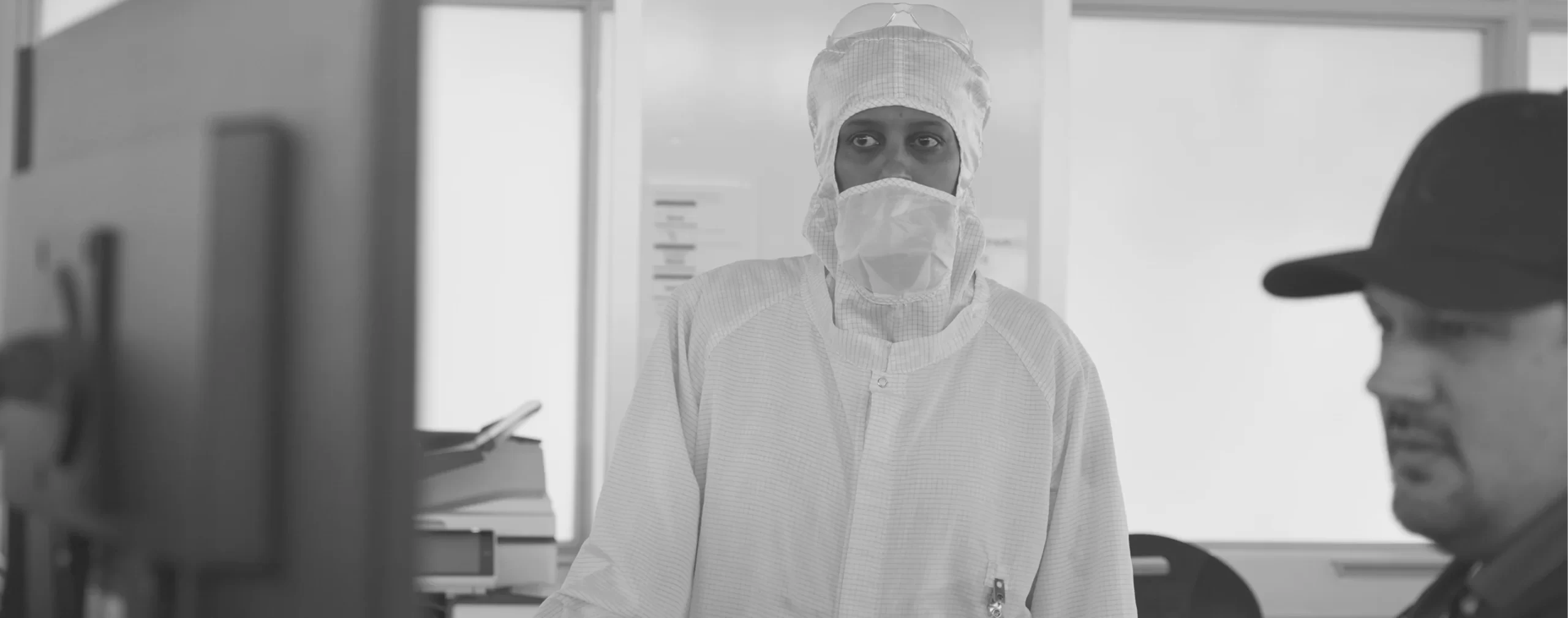 Technicians in cleanroom attire collaborate in a semiconductor fabrication facility.