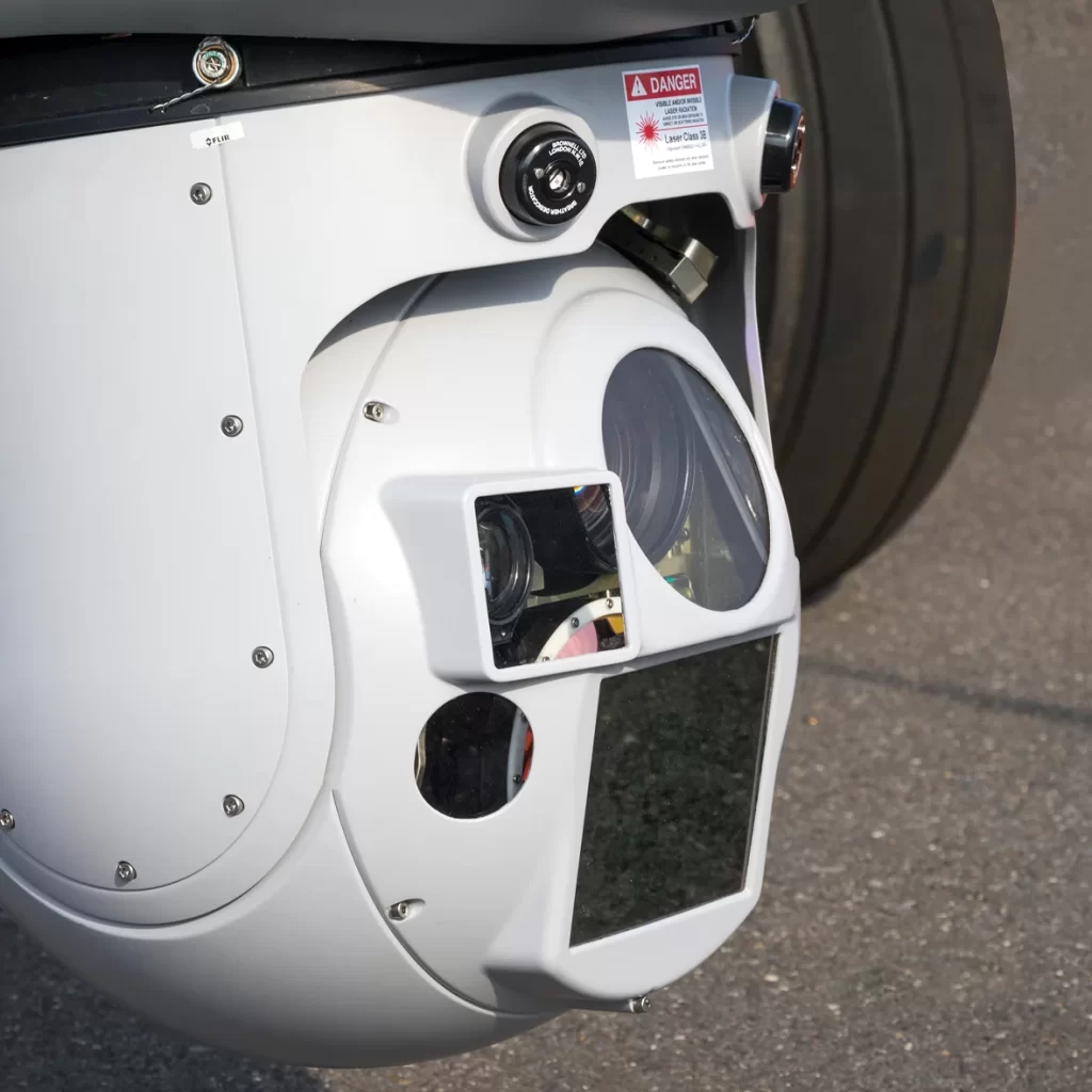 Close-up of a mounted camera system on an aircraft, featuring multiple lenses and sensors, related to SkyWater Technology's Thermaview ROIC solutions.