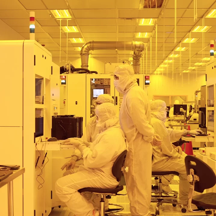 Technicians in cleanroom suits operate equipment at SkyWater Technology's semiconductor fab in Florida.